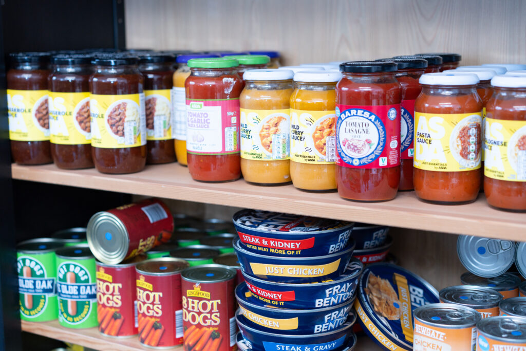 Tins and jars of food on a shelf.