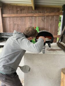 A man putting pizza in a pizza oven