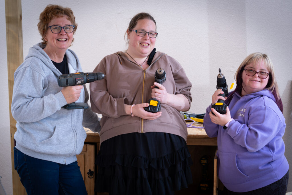 Three women holding drills